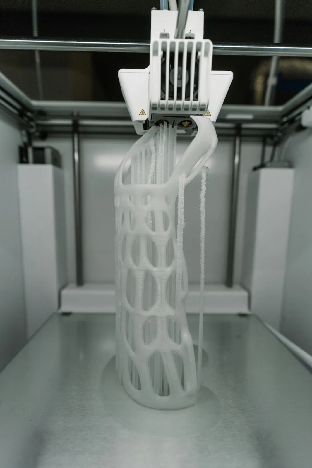 A lattice-structured piece being built up layer by layer on a printer bed